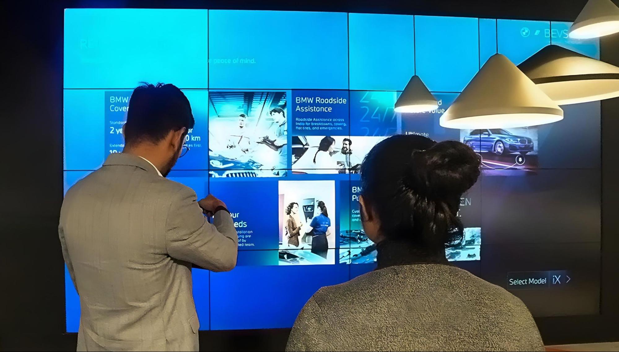 Customers exploring BMW services on digital showroom display
